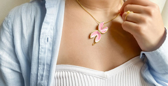 Girl in denim jacket and white shirt wearing a fortune cookie locket that is blush colored inside.